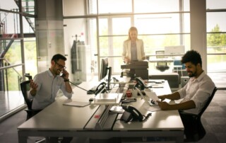 Modern office environment with employees working at desks and a colleague using a business copier in the background, highlighting productivity.