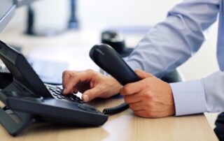 Close up of a businessman making a call on a VoIP phone in an office.